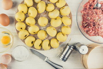 Dumplings raw on a round board. Russian national food. The process of cooking .On the white table