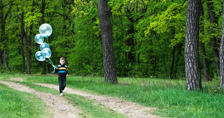 boy with balloons in the green forest