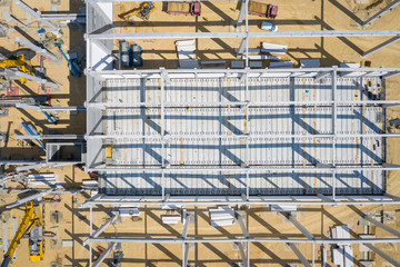 Construction site from above. Top view of factory under construction with heavy machinery. Picture made by drone from above.