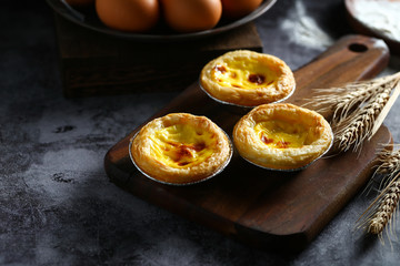 egg tarts on wooden board on dark background