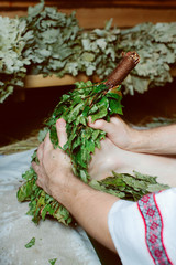 bathhouse attendant is massages the legs of a woman with birch broom. gentle and warm touch