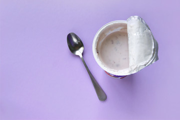 A pink yogurt with strawberry in an open plastic cup on pink background.