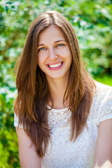 Naklejka premium Close up portrait of beautiful young happy brunette woman with fresh and clean skin, summer street outdoors