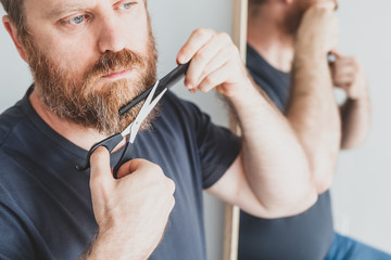 Man cutting moustache and beard himself at home