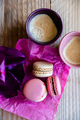 Macarons à la vanille et framboise avec tasses de café sur fond bois