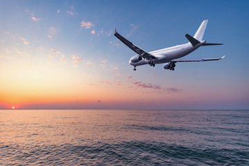 Fototapeta na wymiar Flight of the plane above the ocean before landing at evening time.