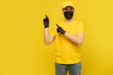 Delivery man in yellow cap, t-shirt uniform, mask gloves isolated on yellow background. Coronavirus 2019-ncov concept