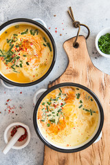 Pumpkin cream soup. Roasted pumpkin and carrot puree soup with turmeric, cream, paprica, chives and pumpkin seeds on grey background. Vegetarian and Vegan recipe. Green living. Organic food.