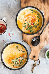 Pumpkin cream soup. Roasted pumpkin and carrot puree soup with turmeric, cream, paprica, chives and pumpkin seeds on grey background. Vegetarian and Vegan recipe. Green living. Organic food.