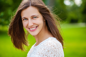 Naklejka premium Close up portrait of beautiful young happy brunette woman with fresh and clean skin, summer street outdoors