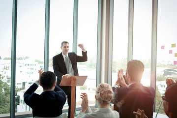 Group of business people sitting on conference together listening to the speaker giving a speech in...