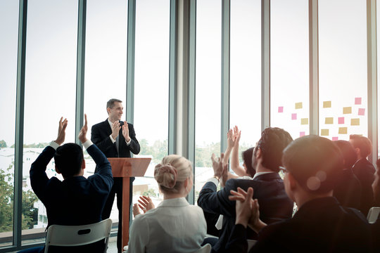 Group of business people sitting on conference together listening to the speaker giving a speech in the meeting room seminar, successful businessman sharing experiences, the audience applauded and cla