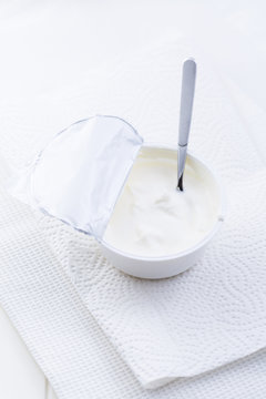 Plain Greek Yogurt in cup with spoon on white background