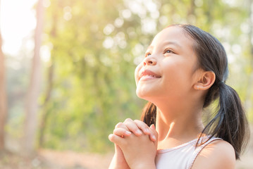 cute little girl hands praying to god with the bible in the morning on nature background.  little asian girl hand praying for thank god. copy space. spirituality and religion faith hope concept.