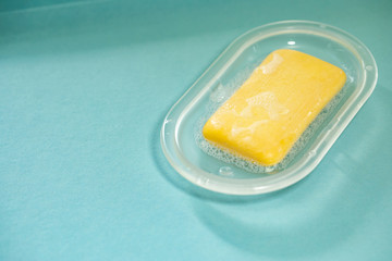 Composition of cleaning and preventive  equipment against COVID-19 on a blue background showing a yellow soap with foam and bubbles