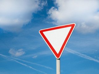 International traffic sign 'Yield sign' or 'Give way'.   Blue sky with some clouds is on background