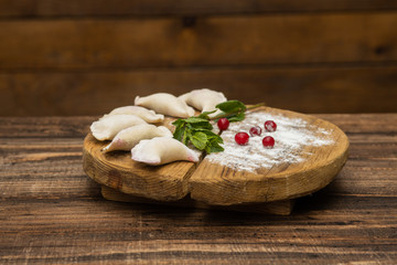 Frozen dumplings with cherry on a wooden plate on a wooden background