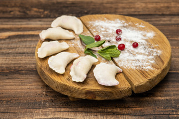 Frozen dumplings with cherry on a wooden plate on a wooden background
