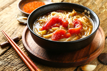tomato noodles in black bowl on wooden table