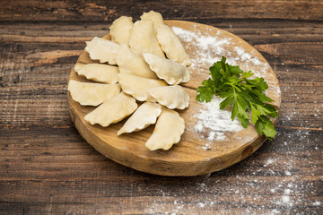 Frozen dumplings on a wooden plate on a wooden background