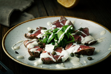 Carpaccio of beef with spices, seasonings and capers on a plate