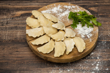 Frozen dumplings on a wooden plate on a wooden background