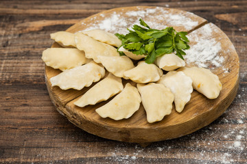 Frozen dumplings on a wooden plate on a wooden background