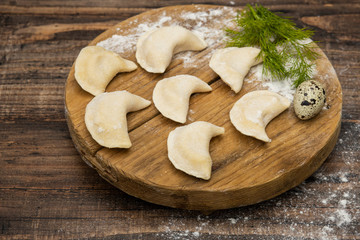 Frozen dumplings on a wooden plate on a wooden background