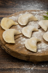Frozen dumplings on a wooden plate on a wooden background
