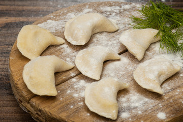 Frozen dumplings on a wooden plate on a wooden background