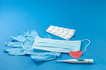 Composition of preventive equipment  against COVID-19 on a blue background showing blue surgical...