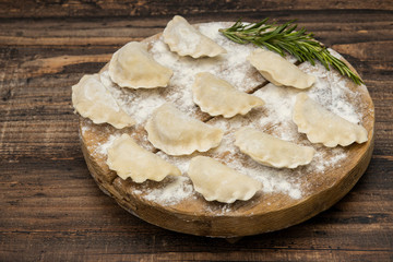 Frozen dumplings on a wooden plate on a wooden background