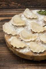 Frozen dumplings on a wooden plate on a wooden background