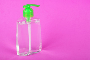 Liquid soap with dispenser on a pink background, place for your text