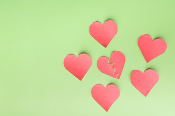 Fototapeta na wymiar Paper hearts on a green background. one inside symbolizes breakup with someone, breakdown, depression