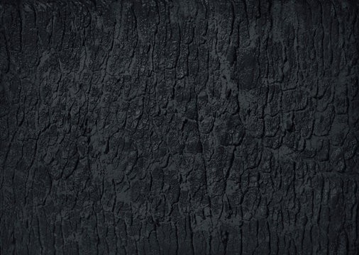 Natural cracked black activated charcoal texture for backgrounds. Top view.
