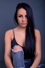 Fototapeta premium Attractive brunette woman posing to camera in grunge jeans