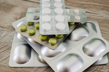 different pills in a blister pack on a wooden background. Close-up.