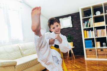 Fototapeta na wymiar Taekwondo boy exercising at home in living room.