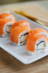 Traditional fresh Japanese sushi rolls with salmon on a white plate.