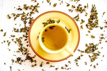 Aromatic green dry tea spread on the table. Green tea served with tea cup.