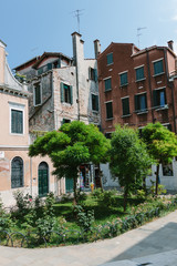 Fototapeta na wymiar Traditional house on street in Venice, Italy. Nobody in sunny day. Italian summer time. Ancient building. Venetian canal with boat. Travel. Inside of yard. Middle day in Italy. Courtyard in house.