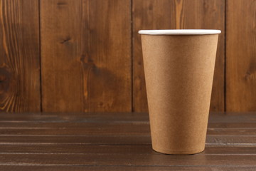 One eco-friendly cardboard cup on a wooden background. The concept of eco-friendly, purity. Mock-up. Copy space.