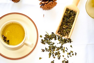 Aromatic green dry tea spread on the table. Green tea served with tea cup.