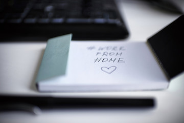 inscription work from home in a notebook on a white background with a keyboard and pen in connection with the coronavirus