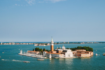 Fototapeta na wymiar Venice in summer time. Italian view. Roof, sea, boats in sunny day. Old city. Popular tourist destination of Italy. Europe. Top view from Saint mark's tower. Cathedral of San Giorgio Maggiore. Isle.