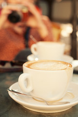 Trendy woman drinking coffee outdoors. Focus on cup.