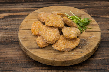 Frozen nuggets  on a wooden plate on a wooden background