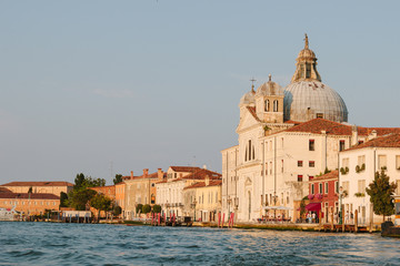 Fototapeta na wymiar Street of Venice in summer time. Italian view. Roof, sea canal, boat in sunny day. Old city, ancient buildings. Italy. Popular tourist destination of Italy. Church of St. Mary the Triumphant. Europe.