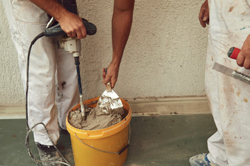 Construction workers plaster a wall.
